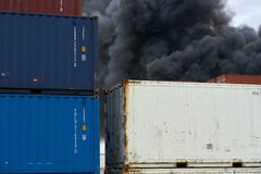 Den abstrakta sikten av sändningsbehållare med putsar av giftlig rök från en industriell brand stiger upp in i himlen arkivbilder Den abstrakta sikten av sändningsbehållare med putsar av giftlig rök från en industriell brand stiger upp in i himlen arkivbilder