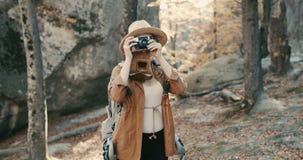 Den aktiva sunda Caucasian kvinnan som tar bilder med en tappningfilmkamera på en skog, vaggar royaltyfria foton Den aktiva sunda Caucasian kvinnan som tar bilder med en tappningfilmkamera på en skog, vaggar royaltyfria foton