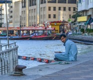 Den arabiska mannen som sitter på, parkerar av Dubai Creek arkivbilder Den arabiska mannen som sitter på, parkerar av Dubai Creek arkivbilder