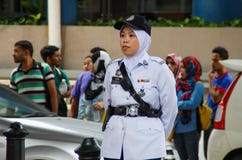 Den asiatiska poliskvinnan står längs vägen i en vit likformig, lock och hijab arkivbilder Den asiatiska poliskvinnan står längs vägen i en vit likformig, lock och hijab arkivbilder