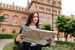Den attraktiva unga kvinnliga turisten undersöker den nya staden Kvinnan med översikten i händer är i sökande av nya affärsföreta royaltyfria bilder Den attraktiva unga kvinnliga turisten undersöker den nya staden Kvinnan med översikten i händer är i sökande av nya affärsföreta royaltyfria bilder