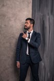Den bra seende stiliga affärsmannen står i hans kontor som pekar fingrar till sidan bärande dräkt och ett band arkivfoto Den bra seende stiliga affärsmannen står i hans kontor som pekar fingrar till sidan bärande dräkt och ett band arkivfoto