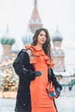 Den Caucasian flickan i en röd klänning rymmer i hand ett dragspel i vinterbakgrunden av St-basilikas domkyrka royaltyfri fotografi Den Caucasian flickan i en röd klänning rymmer i hand ett dragspel i vinterbakgrunden av St-basilikas domkyrka royaltyfri fotografi