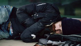 Den drack unga hemlöns man att försöka att sova på papp på bänk på trottoaren arkivbilder Den drack unga hemlöns man att försöka att sova på papp på bänk på trottoaren arkivbilder