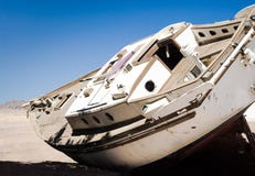 Den gamla yachten ligger på sanden i öknen mot den blåa himlen i Egypten Dahab södra Sinai royaltyfri bild Den gamla yachten ligger på sanden i öknen mot den blåa himlen i Egypten Dahab södra Sinai royaltyfri bild