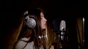 den härliga flickan sjunger barn Ung sångare som sjunger in i en mikrofon Stående som är nära upp av sångaren Inspelningstudio stock video den härliga flickan sjunger barn Ung sångare som sjunger in i en mikrofon Stående som är nära upp av sångaren Inspelningstudio stock video