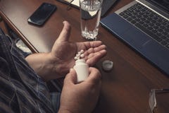 Den höga mannen tar preventivpillerar eller läkarbehandlingminnestavlor eller droger förestående från flaskan hemma arkivbild Den höga mannen tar preventivpillerar eller läkarbehandlingminnestavlor eller droger förestående från flaskan hemma arkivbild