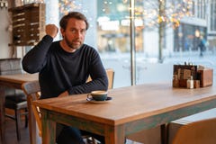 Den ilskna mitt åldrades den caucasian mannen som sitter på tabellen i coffee shop arkivbilder Den ilskna mitt åldrades den caucasian mannen som sitter på tabellen i coffee shop arkivbilder