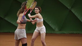 Den kvinnliga tennislagledaren visar tekniken av kuggen med racket till en härlig lång haired flicka på tennisbanan stock video Den kvinnliga tennislagledaren visar tekniken av kuggen med racket till en härlig lång haired flicka på tennisbanan stock video
