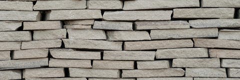 Den lilla bakgrundsväggen tänder - brun textural dekorativ tegelsten royaltyfri foto Den lilla bakgrundsväggen tänder - brun textural dekorativ tegelsten royaltyfri foto