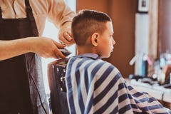 Den lugna lilla skolapojken f?rbereder sig f?r skolan p? den moderiktiga frisersalongen royaltyfri fotografi Den lugna lilla skolapojken f?rbereder sig f?r skolan p? den moderiktiga frisersalongen royaltyfri fotografi