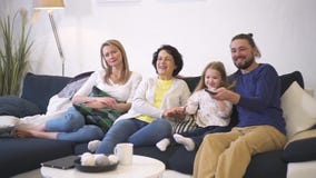 Den lyckliga familjen sitter på soffan tillsammans och hållande ögonen på bra kvalitet för komedifilm på tv stock video Den lyckliga familjen sitter på soffan tillsammans och hållande ögonen på bra kvalitet för komedifilm på tv stock video