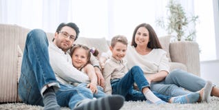 Den lyckliga familjen vilar i vardagsrummet på en fri afton arkivbild Den lyckliga familjen vilar i vardagsrummet på en fri afton arkivbild