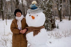 Den lyckliga höga kvinnan hugger och kramar en stor verklig snögubbe Fotografering för Bildbyråer Den lyckliga höga kvinnan hugger och kramar en stor verklig snögubbe Fotografering för Bildbyråer