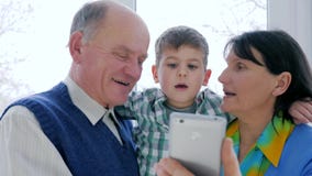 Den lyckliga pensionärfamiljen använder mobiltelefonen för att meddela på internet i rum lager videofilmer Den lyckliga pensionärfamiljen använder mobiltelefonen för att meddela på internet i rum lager videofilmer