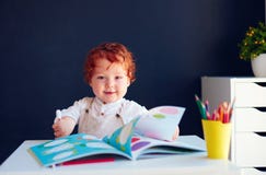 Den lyckliga rödhåriga mannen behandla som ett barn pojketeckningen i framkallande bok på skrivbordet arkivfoto Den lyckliga rödhåriga mannen behandla som ett barn pojketeckningen i framkallande bok på skrivbordet arkivfoto