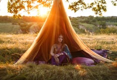 Den lyxiga indiska flickan sitter i ett tält utomhus, på solnedgången royaltyfri fotografi Den lyxiga indiska flickan sitter i ett tält utomhus, på solnedgången royaltyfri fotografi