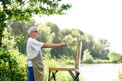 Den manliga målareteckningsbilden på dagen på parkerar mot sjön fotografering för bildbyråer Den manliga målareteckningsbilden på dagen på parkerar mot sjön fotografering för bildbyråer