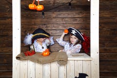 Den roliga pojken och flickan piratkopierar in dräkter i studion med landskap för allhelgonaafton royaltyfria bilder Den roliga pojken och flickan piratkopierar in dräkter i studion med landskap för allhelgonaafton royaltyfria bilder