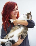 Den röda haired kvinnan ler, medan rymma en stor rasren katt royaltyfri bild Den röda haired kvinnan ler, medan rymma en stor rasren katt royaltyfri bild