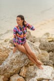 Den sexiga flickan som poserar sammanträde vaggar på, på stranden arkivfoton Den sexiga flickan som poserar sammanträde vaggar på, på stranden arkivfoton