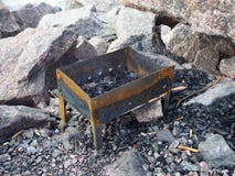 Den tomma metallfyrpannan för att campa på vaggar arkivbild Den tomma metallfyrpannan för att campa på vaggar arkivbild