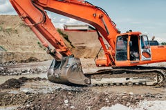 Den tunga industriella grävskopan som arbetar under earthmoving, fungerar på huvudvägkonstruktionsplatsen arkivfoton Den tunga industriella grävskopan som arbetar under earthmoving, fungerar på huvudvägkonstruktionsplatsen arkivfoton