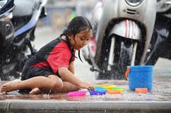 Den unga asiatiska flickan väljer en leksak, som hon spelar i regnet under monsunsäsong i Thailand arkivbilder Den unga asiatiska flickan väljer en leksak, som hon spelar i regnet under monsunsäsong i Thailand arkivbilder
