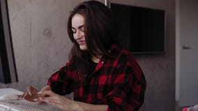 Den unga attraktiva flickan är emotionell om något, medan att skriva som sitter i en hemtrevlig vardagsrum stock video Den unga attraktiva flickan är emotionell om något, medan att skriva som sitter i en hemtrevlig vardagsrum stock video
