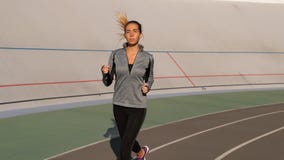 Den unga brunettkvinnan kör i morgonen på sportspår royaltyfri foto Den unga brunettkvinnan kör i morgonen på sportspår royaltyfri foto