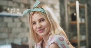 Den unga kvinnan med en attraktiv framsidastående för blont hår som ser rak till kameran och hon, ler gulligt har hänglsen stock video Den unga kvinnan med en attraktiv framsidastående för blont hår som ser rak till kameran och hon, ler gulligt har hänglsen stock video