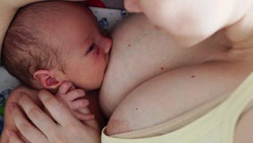 Den unga kvinnan som ammar hennes litet, behandla som ett barn hemma, closeupen arkivfilmer Den unga kvinnan som ammar hennes litet, behandla som ett barn hemma, closeupen arkivfilmer