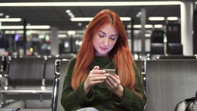 Den unga kvinnlign använder telefonen i flygplatsterminal Den unga kvinnlign använder telefonen i flygplatsterminal