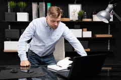 Den unga mannen står nära de datortabellen och blickarna på bildskärmen fotografering för bildbyråer Den unga mannen står nära de datortabellen och blickarna på bildskärmen fotografering för bildbyråer