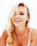 Den unga nätta blonda kvinnan i säng täckt vit täcker att le che Royaltyfri Foto Den unga nätta blonda kvinnan i säng täckt vit täcker att le che Royaltyfri Foto