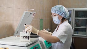 Den yrkesmässiga kvinnliga medicinska assistenten i vit skurar, för den skyddande maskeringen, lock- och latexhandskar som drar p lager videofilmer Den yrkesmässiga kvinnliga medicinska assistenten i vit skurar, för den skyddande maskeringen, lock- och latexhandskar som drar p lager videofilmer