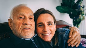 Den äldre mannen kramar hans vuxna sondotter hemma arkivfoto Den äldre mannen kramar hans vuxna sondotter hemma arkivfoto