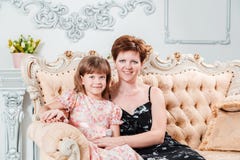 dengamla kvinnan kramar engammal flicka som sitter på en härlig soffa som ser kameran royaltyfri foto dengamla kvinnan kramar engammal flicka som sitter på en härlig soffa som ser kameran royaltyfri foto
