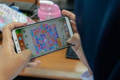 DENPASAR/BALI-MARCH 27 2019: en kvinna som använder en hijab, är kall spela lekar på hennes mobiltelefon, medan vänta på tiden at arkivbilder DENPASAR/BALI-MARCH 27 2019: en kvinna som använder en hijab, är kall spela lekar på hennes mobiltelefon, medan vänta på tiden at arkivbilder