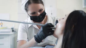 Dente das brocas do dentista ao paciente na clínica dental, movimento lento Conceito do stomatology filme Dente das brocas do dentista ao paciente na clínica dental, movimento lento Conceito do stomatology filme