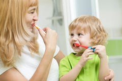 Dentes de escovadela bonitos da mãe e da criança no banheiro imagens de stock Dentes de escovadela bonitos da mãe e da criança no banheiro imagens de stock