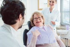 Dentist and assistant greeting senior patient stock photos Dentist and assistant greeting senior patient stock photos