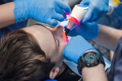 A dentist and an assistant treat the teeth of a young man. Teenager in dentistry. royalty free stock image A dentist and an assistant treat the teeth of a young man. Teenager in dentistry. royalty free stock image