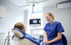 Dentista de sexo femenino feliz con la muchacha paciente en la clínica imagen de archivo libre de regalías Dentista de sexo femenino feliz con la muchacha paciente en la clínica imagen de archivo libre de regalías