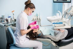 Dentista fêmea com ferramentas dentais - espelhe e sonde a verificação acima dos dentes pacientes no escritório dental da clínica imagens de stock Dentista fêmea com ferramentas dentais - espelhe e sonde a verificação acima dos dentes pacientes no escritório dental da clínica imagens de stock