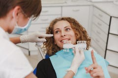 Dentista que compara a máscara paciente dos dentes do ` s com as amostras para o tratamento do descoramento fotos de stock royalty free Dentista que compara a máscara paciente dos dentes do ` s com as amostras para o tratamento do descoramento fotos de stock royalty free