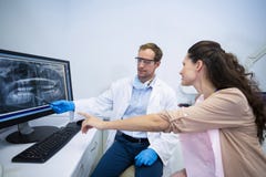 Dentista que muestra una radiografía de dientes al paciente femenino Fotos de archivo libres de regalías Dentista que muestra una radiografía de dientes al paciente femenino Fotos de archivo libres de regalías