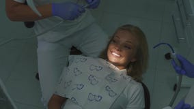 Dentista que trata os dentes pacientes louros fêmeas com a ajuda da máquina da rebarba Close-up filme Dentista que trata os dentes pacientes louros fêmeas com a ajuda da máquina da rebarba Close-up filme