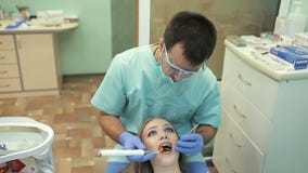 Dentista que usa la lámpara ULTRAVIOLETA de curado dental en los dientes del paciente almacen de metraje de vídeo Dentista que usa la lámpara ULTRAVIOLETA de curado dental en los dientes del paciente almacen de metraje de vídeo