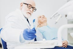 Dentiste masculin calme remettant le miroir dentaire image stock Dentiste masculin calme remettant le miroir dentaire image stock